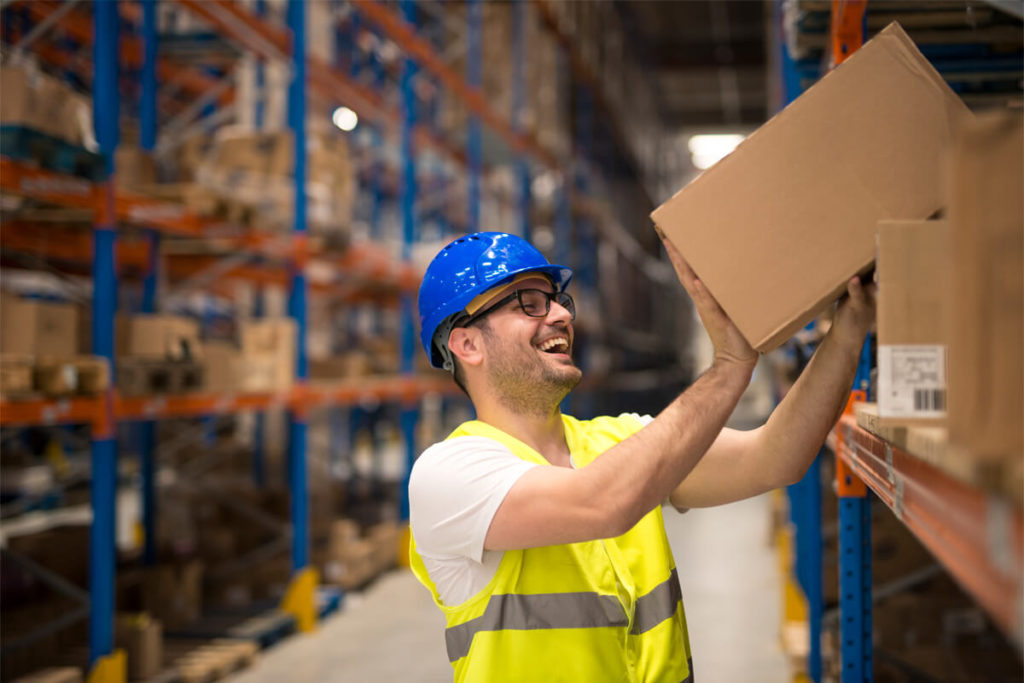 male employee placing a box on a shelf while laughing